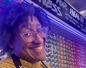 Kristen smiling in front of the Lush Tysons Corner Center Bath Bomb Wall